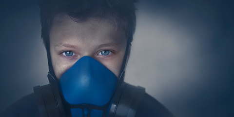 Young boy wearing gasmask, respirator portrait. Effects of worldwide air pollution, industrial...