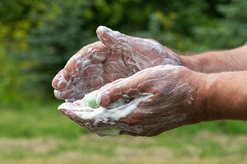 Hand washing with soap outdoors.