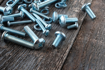 Metal screws, fasteners on a wooden background.