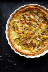 Mushroom quiche with addition chanterelle mushrooms and brown mushrooms on a black background, top...