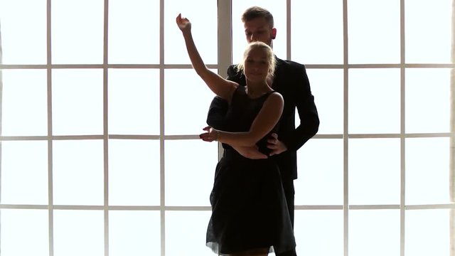 Talented professional artists dancing contemporary dance. Slow motion couple of stylish ballet dancers practicing beautiful dance in studio. Checkered window background.