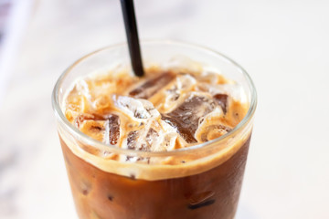 Iced coffee glass with black straw on table in cafe and restaurant.