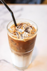 Iced coffee glass with black straw on table in cafe and restaurant.