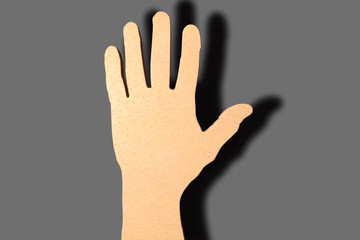 The cardboard mans hand casts a shadow on the wall.