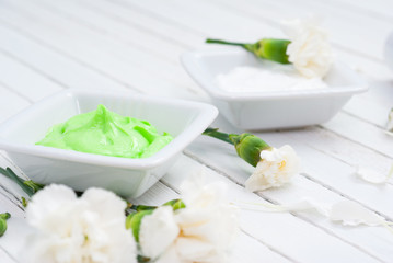 cosmetic creams, perfume in pipette and white flowers on bright wooden