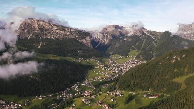 Beautiful aerial view of small town near the mountains during sunset. Clouds covering mountains and moving fast