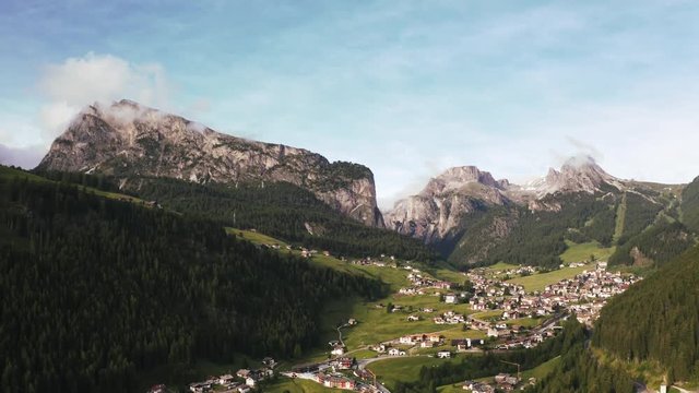 Beautiful aerial view of small town near the mountains during sunset. Clouds covering mountains and moving fast