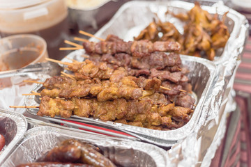 Tasty pork BBQ skewers in aluminum foil tray at local market in America
