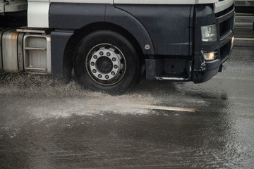 Truck rides through a puddle. Tractor rushing on the highway. Wheel cargo car. Diesel fuel rides around the city.