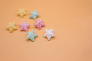Beautiful colorful stars props placed on orange background creative top view, christmas decoration background