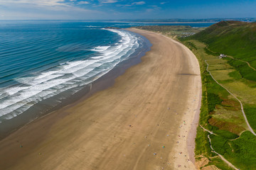 Fototapeta na wymiar Aerial view of the huge sandy beach and green hills in Rhossili, Swansea