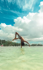 Young man doing acrobatics in the water in tropical location