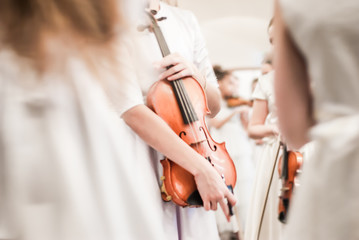Blurred background image of young girls violinists in white dresses before the concert.