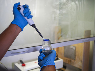 men's hands scientists are using aquatic release micropipette into the test tube. The process of research and development in laboratory science