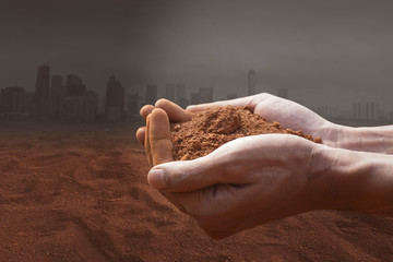 Plants and climate change with the concept of global warming. Hand holding the red soil.