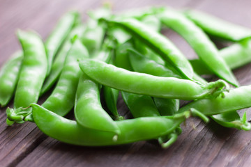 young ripe and juicy pods of green peas on wooden background