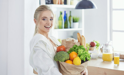 Young woman holding grocery shopping bag with vegetables Standi