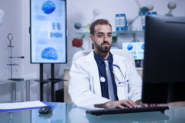 Motivated handsome young doctor working on his computer in the hospital office
