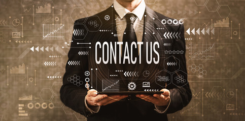 Contact us with businessman holding a tablet computer on a dark vintage background