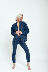 Confident and sexy. Full length of attractive young woman in jeans wear looking aside while standing against grey background in studio © Friends Stock