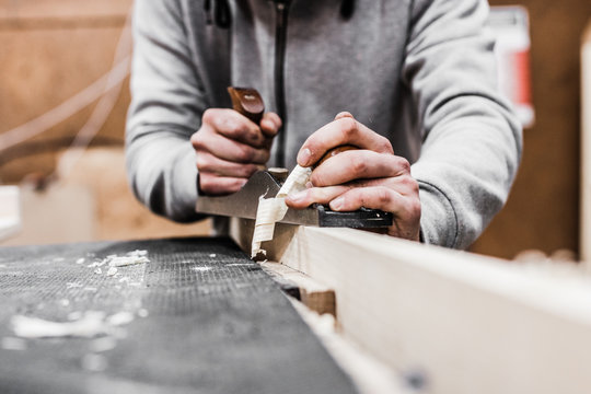 carpenter plaining wood, with wood shavings