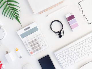 top view of office desk table with  calculator, notebook, plastic plant, smartphone and keyboard on white background, graphic designer, Creative Designer concept.