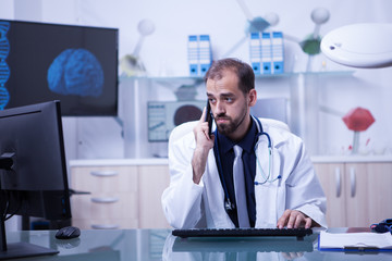 Male doctor having a video conference and talking on the phone with a patient
