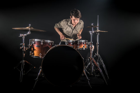 Professional drummer playing on drum set on stage on the black background