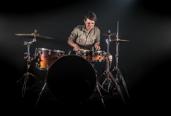 Fototapeta premium Professional drummer playing on drum set on stage on the black background
