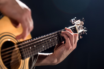 Guitarist, music. A young man plays an acoustic guitar on a black isolated background