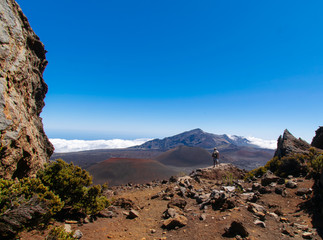 person standing on a stone with a view of crater and clouds