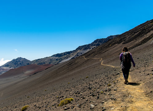 woman with backpack walking in a crater of an inactive volcano