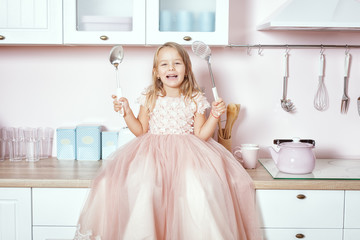 Beautiful little girl in the kitchen and laughs.