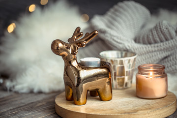 Fototapeta na wymiar Christmas festive background with toy deer, golden lights and candles, wooden deck table