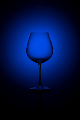 Empty tall wine glass on a black and blue background