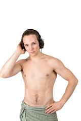 Fototapeta premium Handsome naked young man in towel listening to music in headphones on white background isolated