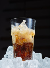 Glass of soda with ice on a dark background. Carbonated beverages. Close up.