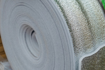 A roll of insulation with foil. The concept of building houses and pipe insulation.