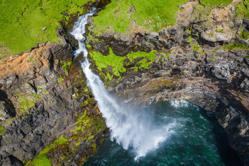 Aerial view of Mulafossur waterfall in Gasadalur village in Faroe Islands, North Atlantic Ocean. Photo made by drone from above. Nordic Natural Landscape.