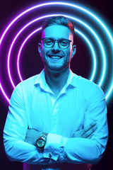 Young handsome model posing in a studio in a trendy neon light. Fashionable man in a stylish suit. Vibrant color. Bright colorful light effects. Disco style. Overlay. Gel filter. Supersaturated