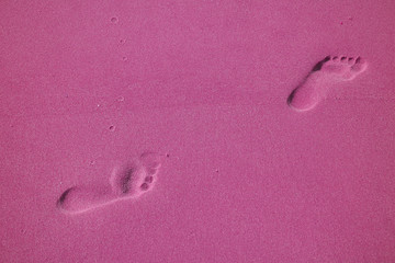Pop art styled woman's walking footprints on the sand beach in magenta color