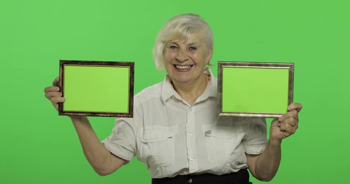 An elderly woman holding two frames with green image. Grandmother. Chroma key