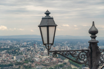 Street lamp close-up with the background on Tbilisi from Mount Mtantsminda in regional weather