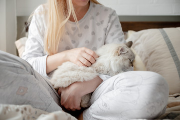 Blonde Giirl hygge with fluffy cat, pajama and blanket. Hugge and lagom concept comfort and simple life . Horizontal copyspace