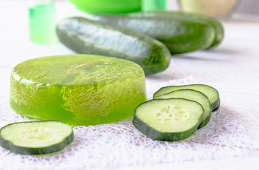 Green cucumber soap on a white background with cucumber slices. Spa treatments with cucumber soap.