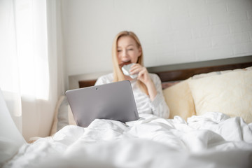 Work from home concept . Blonde Giirl typing and using laptop eating chocolate. Hygge Horizontal copyspace