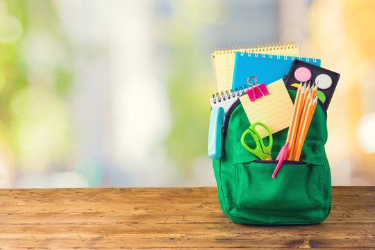 Back to school concept with bag backpack and school supplies on wooden table over abstract background