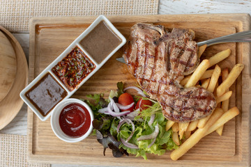 Top view of a set of stake, grilled meat with French fries and variety of dipping sources