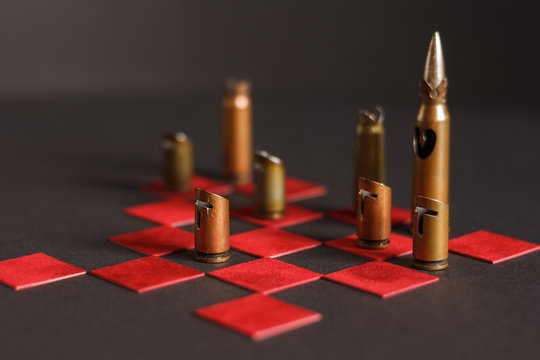 A hand-crafted chess pieces made of bullet shells (7.62x54 mm and 7.62x39 mm caliber). Chess game. Dark background. The small depth of field