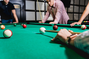 Young man trying to hit the ball in billiard.